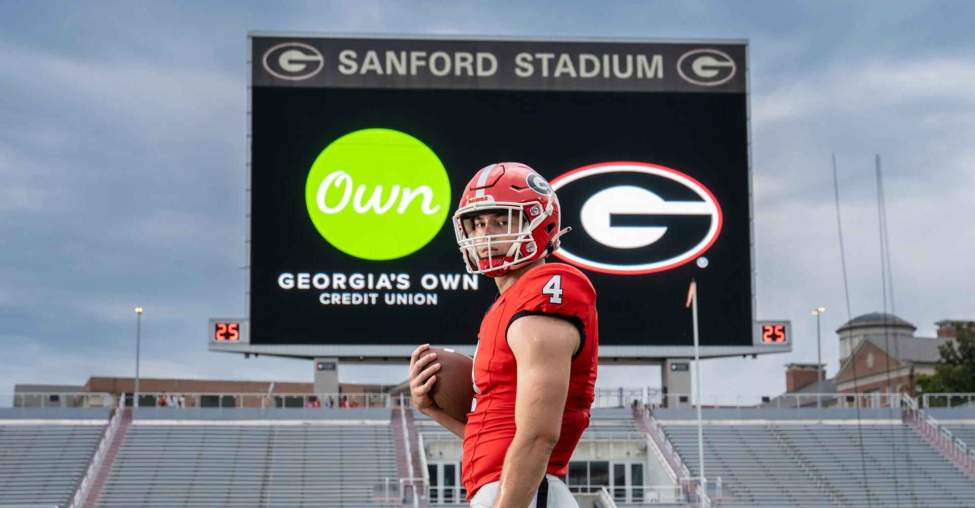 Oscar Delp in Sanford Stadium in front of a video board that shows the GOCU logo.