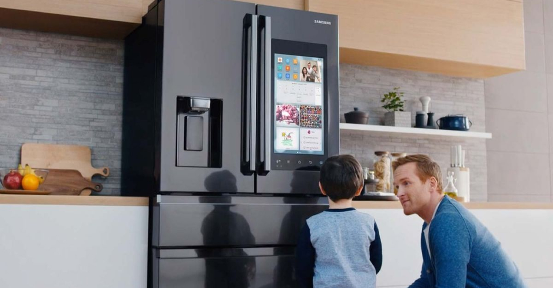 Modern Samsung refrigerator with a touchscreen panel, operated by a father and son.