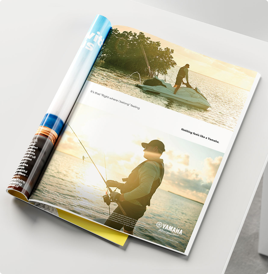 Open magazine pages showing a scenic waterside image with a man fishing.