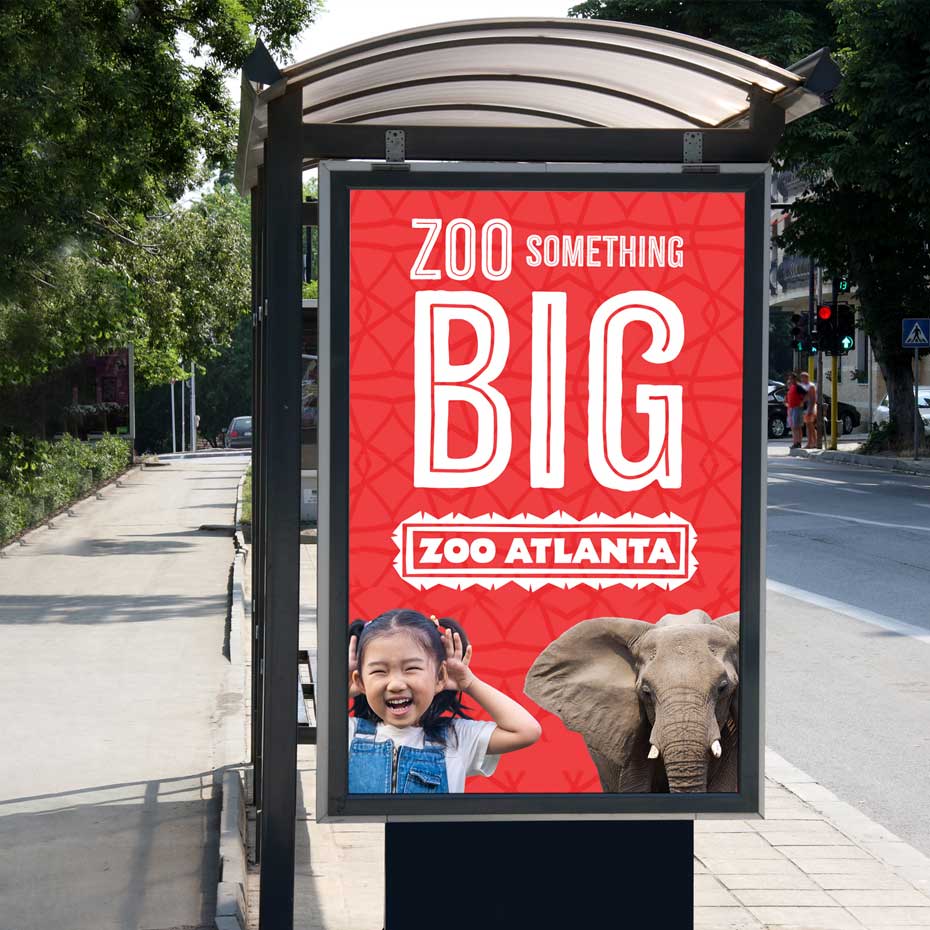 Bus stop advertisement featuring text “Zoo Something BIG,” with a girl and an elephant