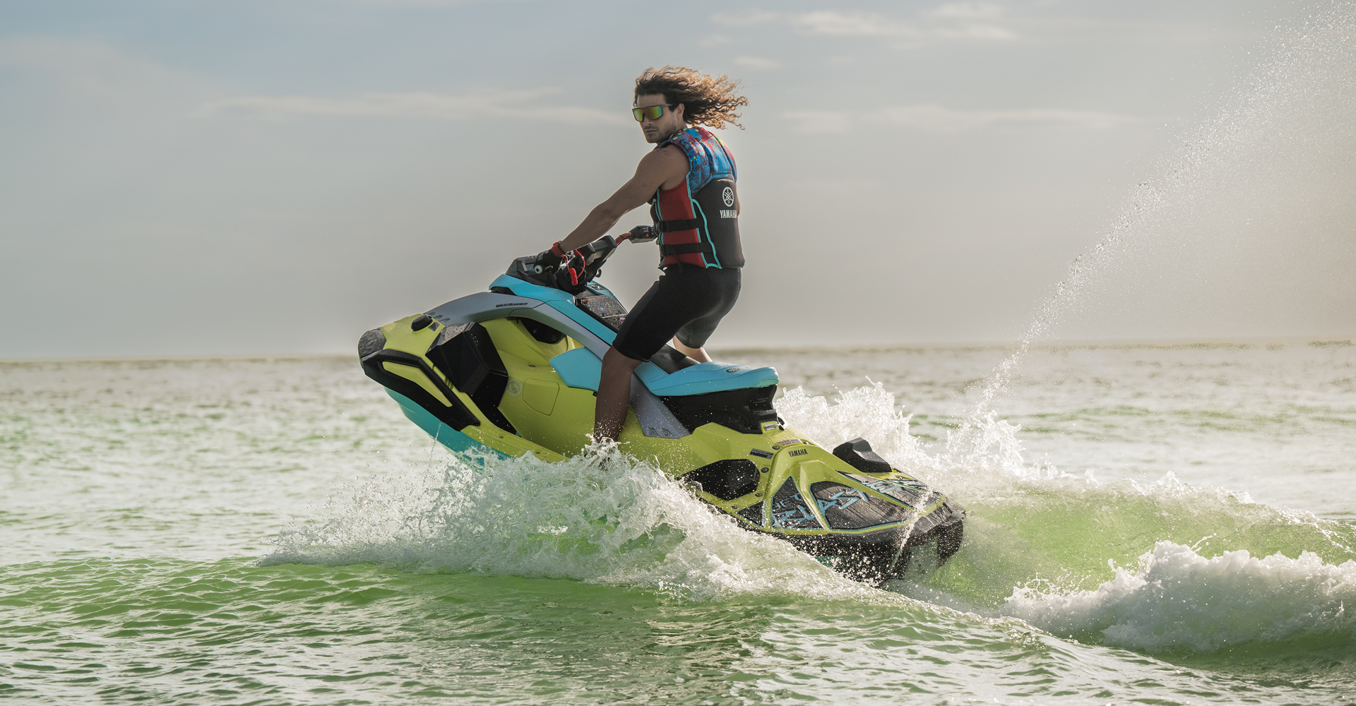 Teenager riding a personal watercraft with water splashing upward.