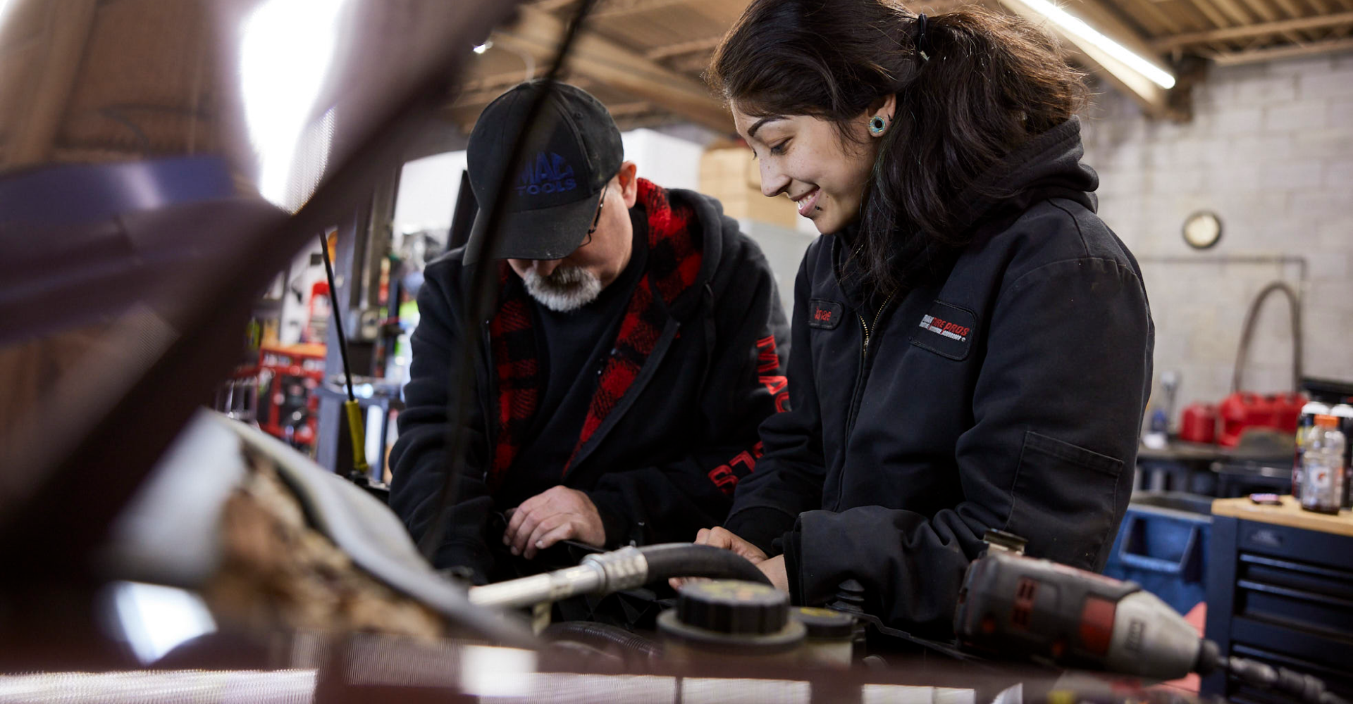 Two technicians in a workshop, examining or repairing a piece of equipment.