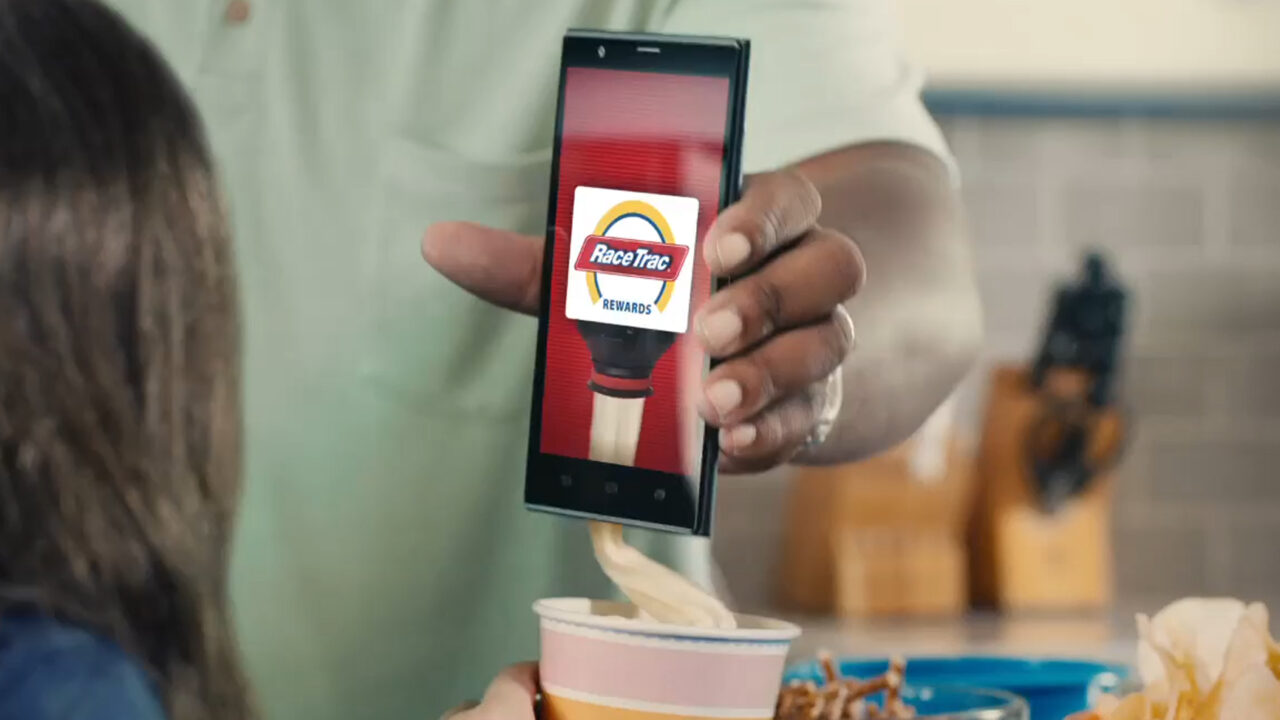 Phone screen displaying the Racetrac app in someone’s hand. The phone is dispensing soft serve.