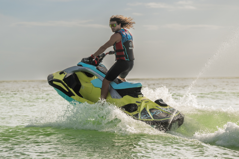 Teenager riding a personal watercraft with water splashing upward.